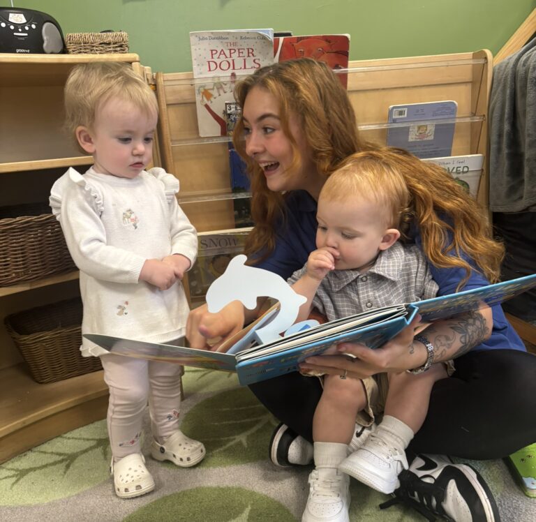 a nursery apprentice reading to two toddlers