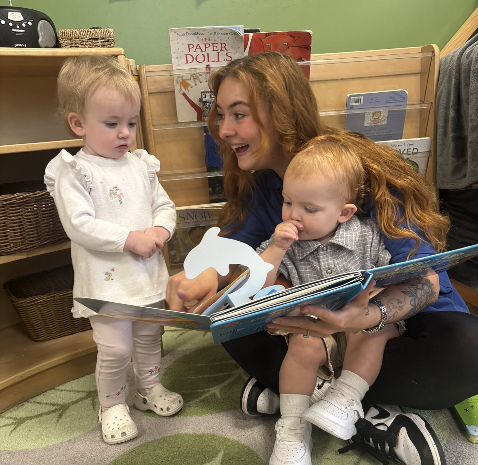 a nursery apprentice reading to two toddlers